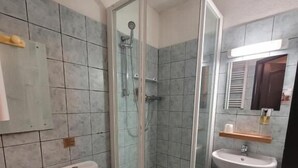 A bathroom with a toilet, a shower with a glass door, and a sink. - L'étape (Les Omergues)
