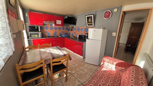 A compact kitchen with red cabinets, a microwave, a toaster, and a refrigerator.