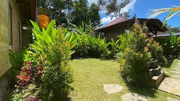 A garden with a lawn, stone pathways, and a building with a tiled roof.