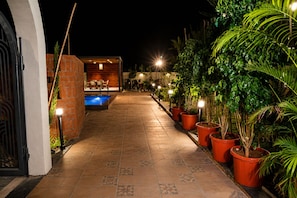 A pathway leading to a pool area with potted plants and outdoor seating. - Nakshatra Aura (Indore)