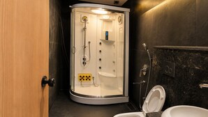 Un baño moderno con ducha envuelta en vidrio, inodoro blanco y lavamanos de mármol.