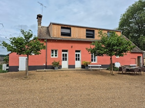 A two-story building with a red facade, a chimney, and a white door.