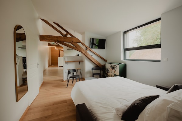 Un dormitorio con cama, escritorio, silla y ventana.