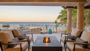 Eine Terrasse mit Blick auf den Strand, Sitzgelegenheiten im Freien und einer Feuerstelle.