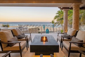 A terrace with a view of the beach, outdoor seating, and a fire feature. - Casa Keller: Beachfront in Pedregal | 2 Swimming Pools (Cabo San Lucas)