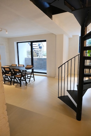 Ein Essbereich mit Tisch und Stühlen, eine Treppe und Blick durch ein großes Fenster.