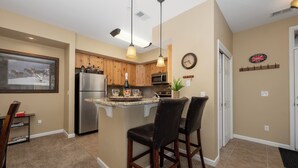A kitchen with a central island, wooden cabinets, stainless steel appliances, pendant lighting, and a clock on the wall. - Timbers 9-4 New, spacious condo in Fraser, private deck and more! (Fraser)