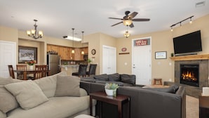 A living room with a sectional sofa, a fireplace, a television, and a ceiling fan. - Timbers 9-4 New, spacious condo in Fraser, private deck and more! (Fraser)