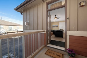A residential entryway with a balcony, a welcome mat, and a door leading to a living room with a couch and a ceiling fan. - New, spacious condo in Fraser, private deck and more! (Fraser)