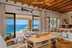 Ein geräumiges Wohnzimmer mit großem Fenster zum Meerblick, einer Holzbalkendecke und einer gemütlichen Sitzecke.