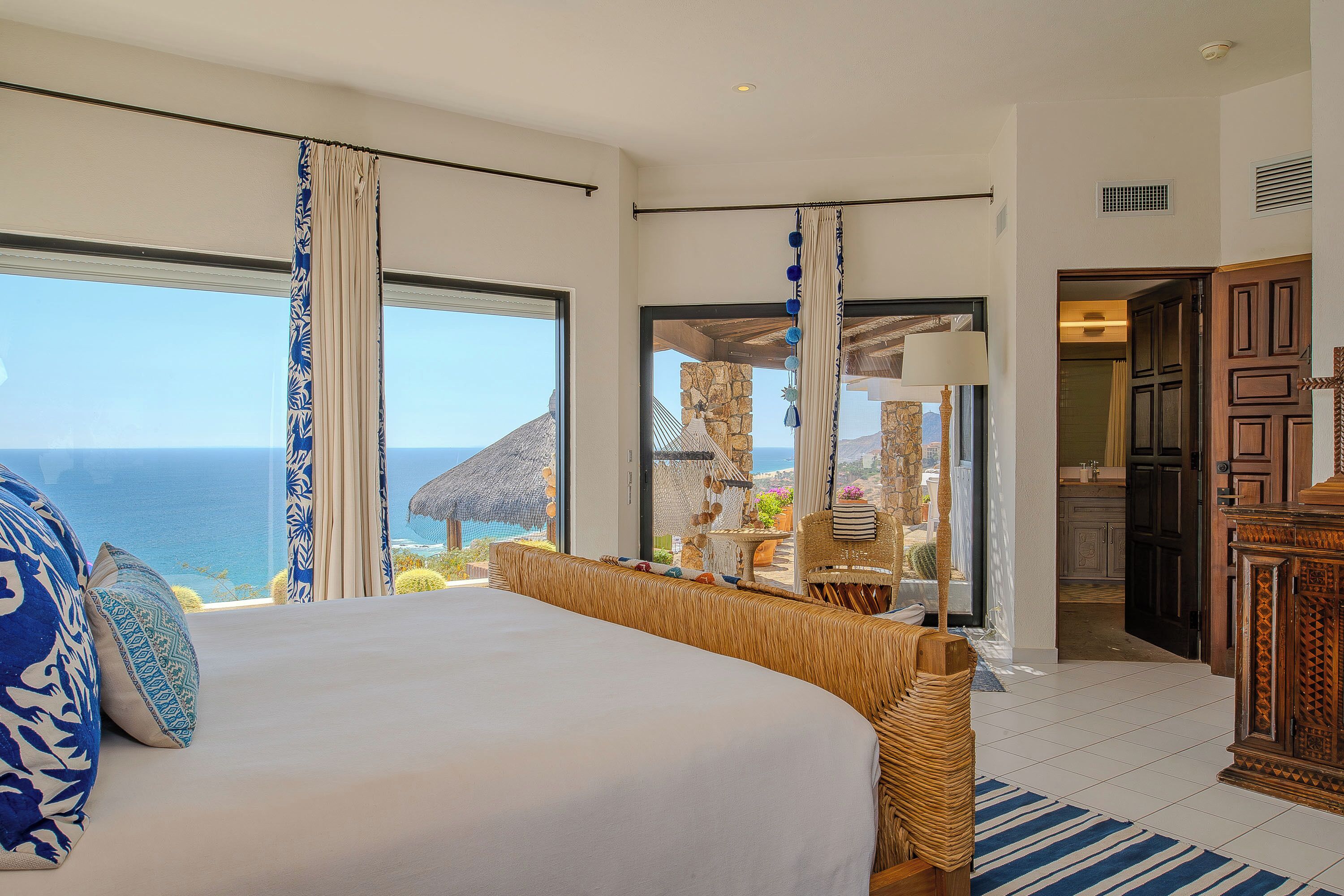 A bedroom with a large bed, a view of the ocean, and a door leading to a bathroom.