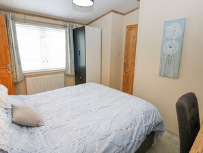 Un dormitorio con cama, ventana con cortinas, radiador, armario, puerta y una obra de arte colgada en la pared.