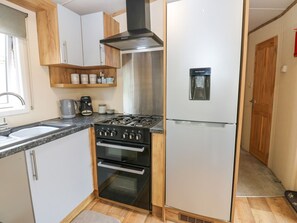 Eine kleine Küche mit Gaskochfeld, Backofen und Kühlschrank.