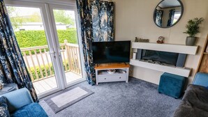 A living room with a TV, sofa, and a balcony with curtains. - Plot 41 (Carlisle)