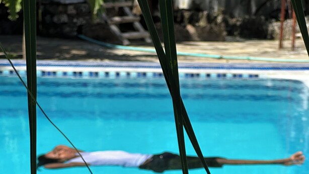 A swimming pool with a person floating on a floatation device. - Heidi’s Beach Stay (Mombasa)