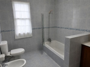 Une salle de bain équipée de toilettes, d’un bidet et d’une baignoire.