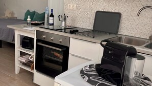 Una cocina compacta con horno empotrado, cafetera y microondas.