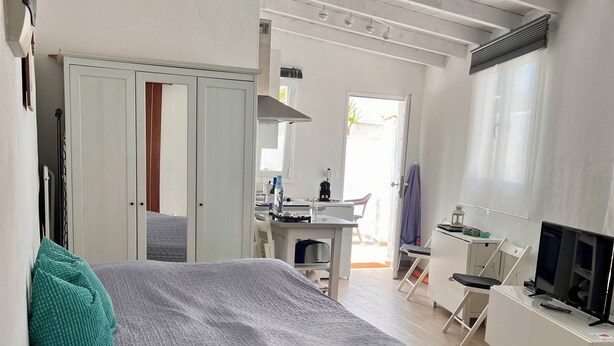 Un dormitorio con cama, escritorio, televisor y armario.