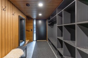 Un pasillo con paredes de madera, una puerta negra y piso alfombrado.