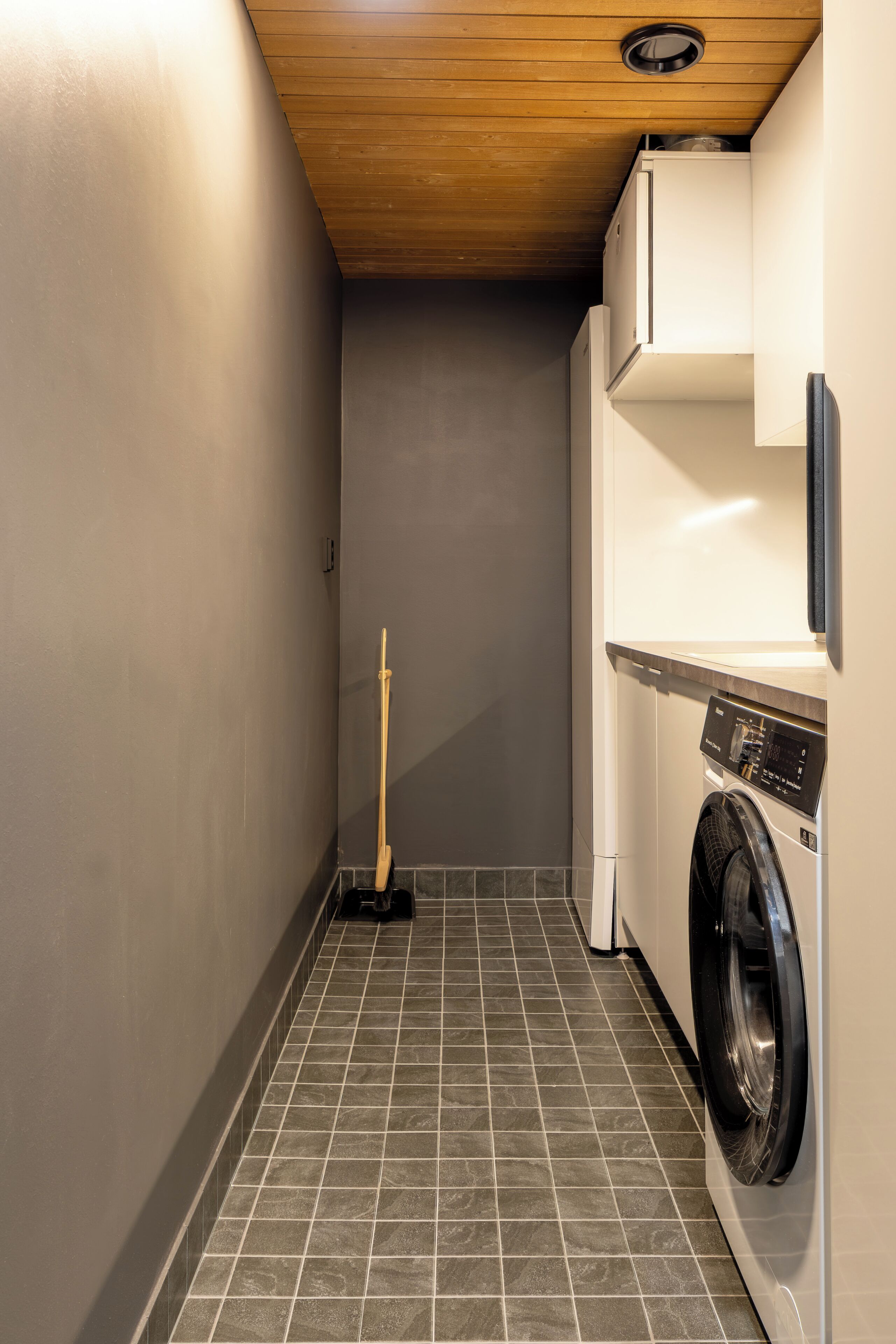 Een wasserette met een wasmachine, een dweil en een houten plafond.