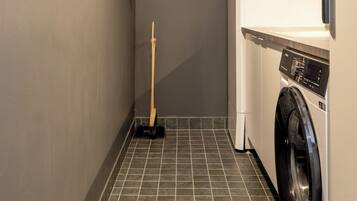 Een wasserette met een wasmachine, een dweil en een houten plafond.