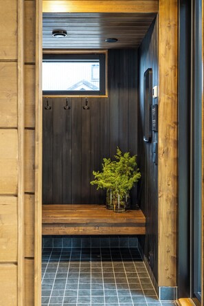 Un interior de madera con un banco, una planta pequeña y una ventana.