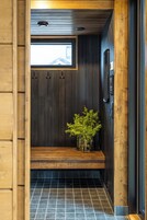 Un interior de madera con un banco, una planta pequeña y una ventana.