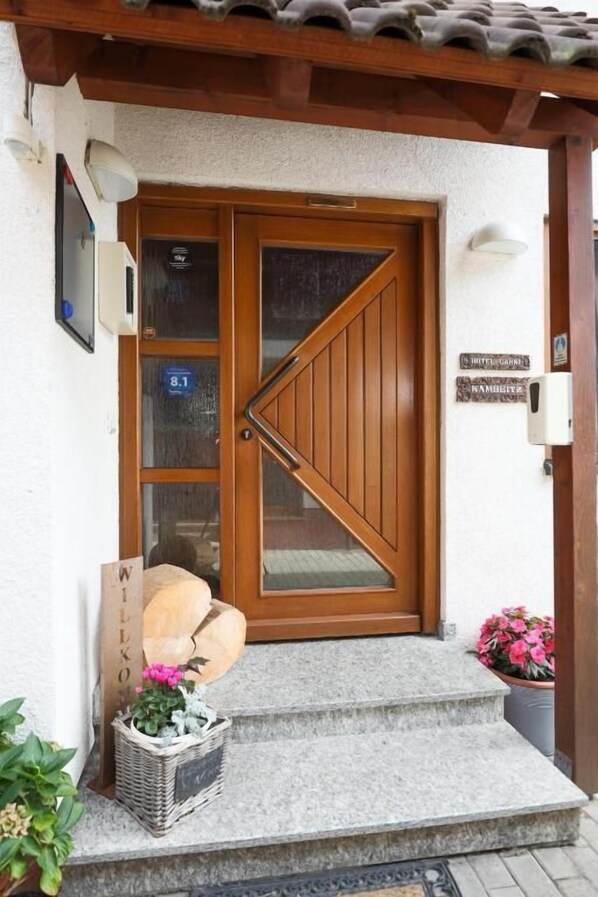 Eine Holztür mit Glasschieber, einem Willkommensschild und einer Treppe zum Eingang.