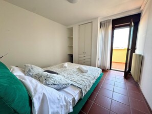 Ein Schlafzimmer mit einem Bett, einem grünen Kissen, einem flauschigen Kissen, einem weißen Handtuch und einem Kleiderschrank.