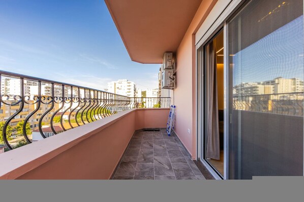 Ein Balkon mit Metallgeländer, einer Glastür und Blick auf Gebäude.