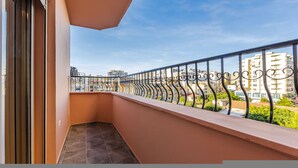 Ein Balkon mit Metallgeländer, ein klarer Himmel und Gebäude im Hintergrund.