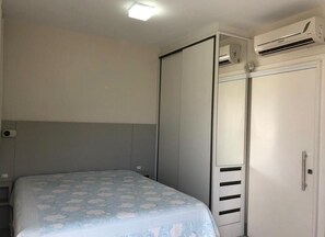 Ein Schlafzimmer mit Bett, Kleiderschrank und Klimaanlage.
