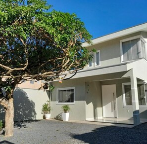Ein modernes, zweistöckiges Haus mit Auffahrt, Kübelpflanzen und einem Baum im Vordergrund.