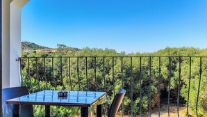 Ein Balkon mit Tisch und Stühlen, mit Blick auf einen Weinberg und entfernte Gebäude.