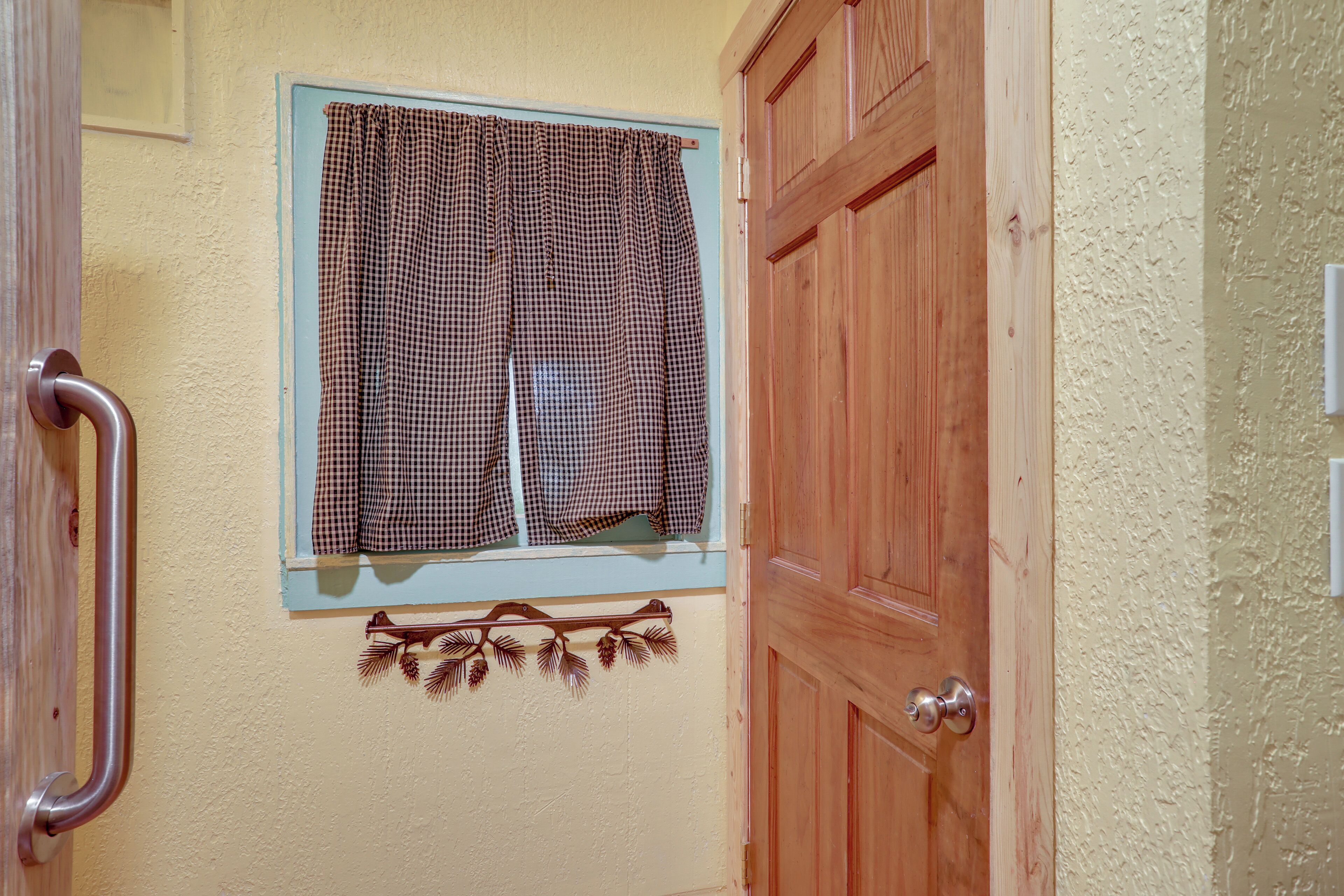 A wooden door with a window above it, a metal handle, and a wall-mounted decoration.