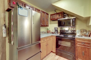 A kitchen with wooden cabinets, stainless steel appliances, and a microwave. - Home Near Eleven Point River & Nat'l Forest! (Alton)