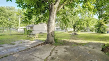 A residential property with a large tree, a picnic table, and a house in the background.