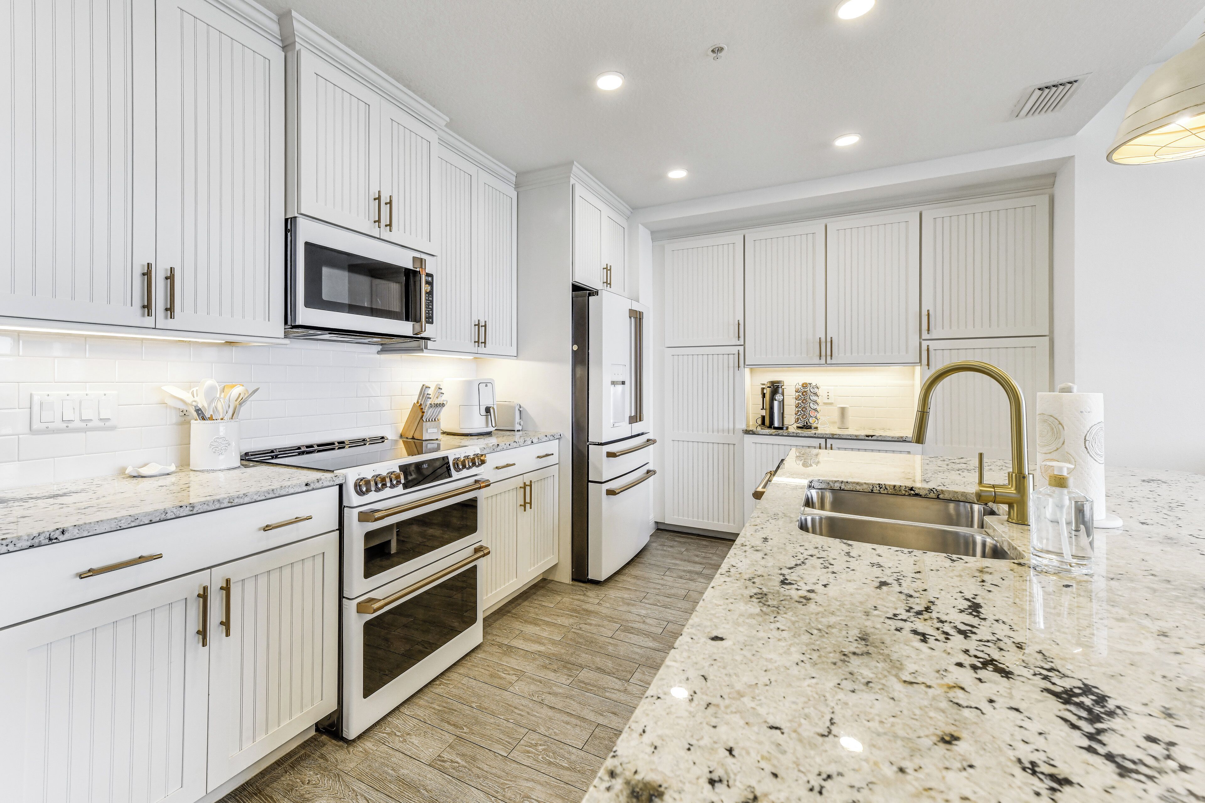 A modern kitchen with white cabinetry, stainless steel appliances, and a granite countertop.