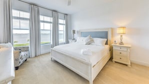 Ein Schlafzimmer mit Bett, Nachttisch, Lampe, Stuhl und Blick ins Freie.