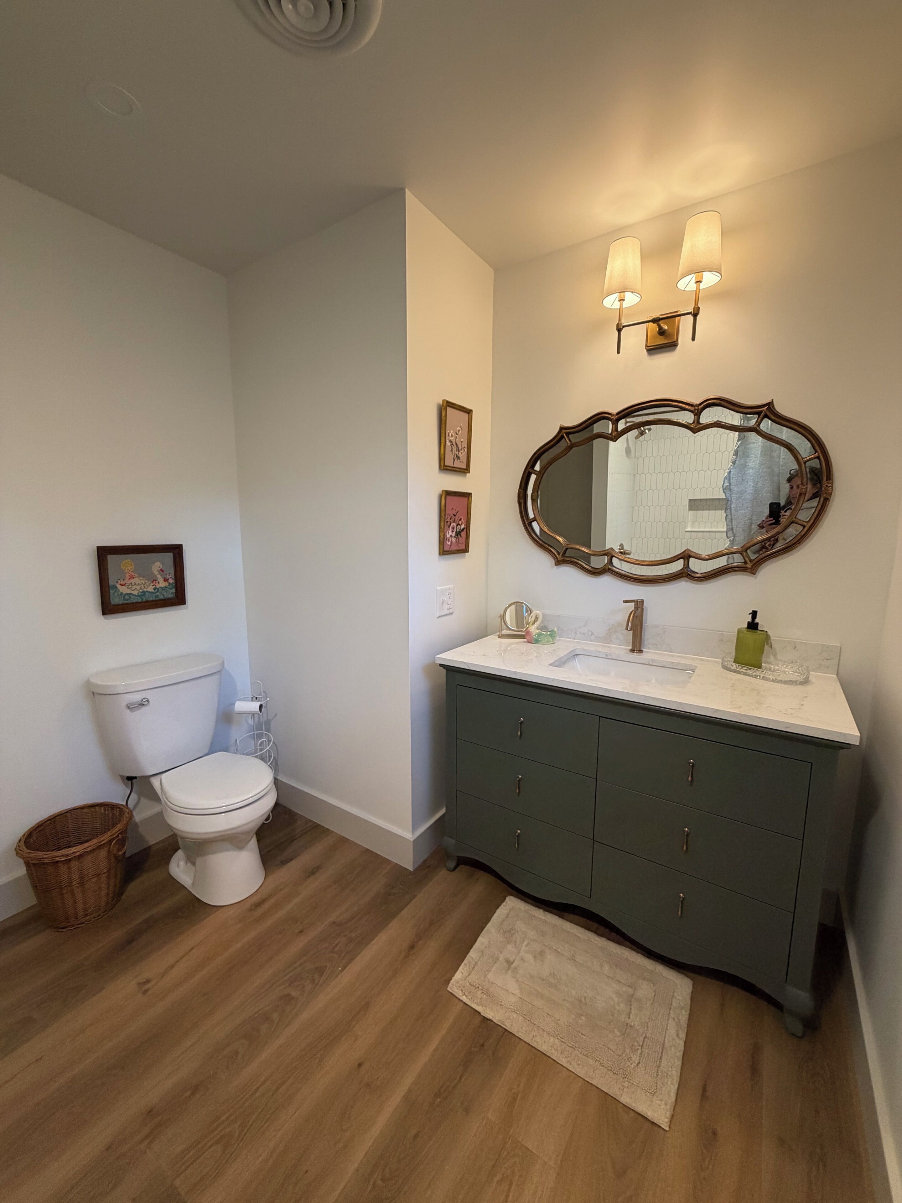 A bathroom with a toilet, vanity, mirror, and two wall-mounted lights.