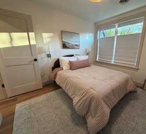 Una camera da letto con un letto, un quadro, una finestra con persiane e una porta.