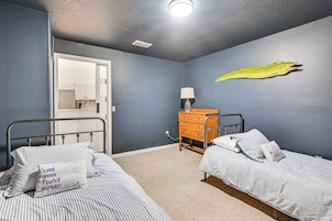 A bedroom with two beds, a dresser, a lamp, and a wall decoration.