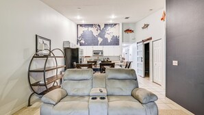 En moderne stue med en sofa, et verdenskort på væggen og et køkken i baggrunden.