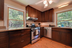 A kitchen with wooden cabinets, a stainless steel stove, and a dishwasher. - Waterfront Cottage! Family-friendly Hideaway (Round Pond)