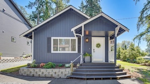 A two-story house with a front porch, a small garden, and a driveway. - Walk to Spanaway Lake: Chic Home w/ Rooftop Deck! (Spanaway)