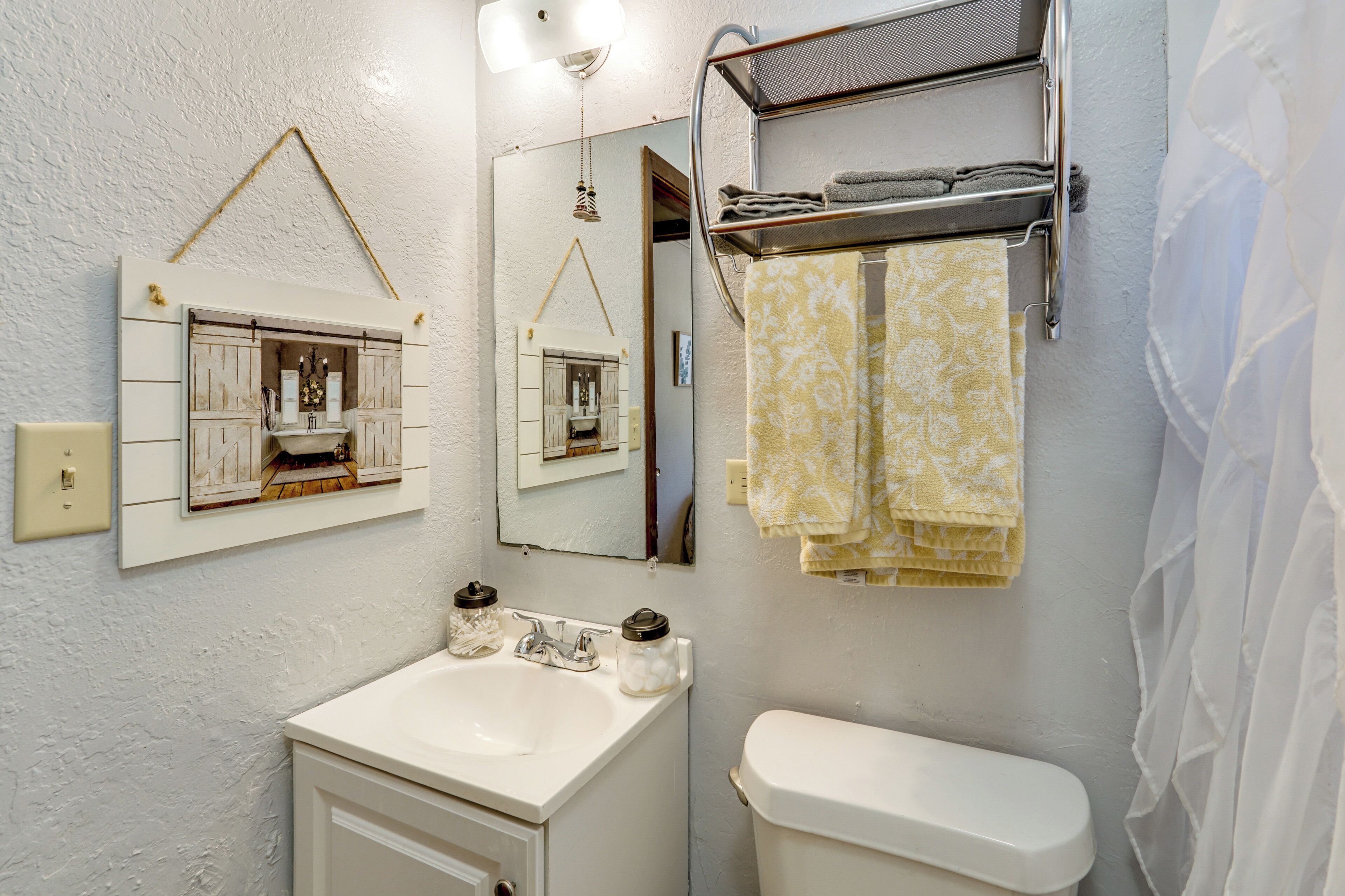 Ein Badezimmer mit Waschbecken, Spiegel, Handtuchhalter und Toilette.