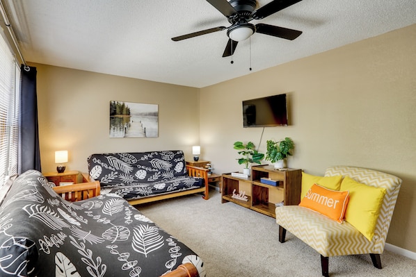 A living room with a sofa, a chair, a TV, a ceiling fan, and a painting on the wall. - 1 Mi to Marina! Family Lake of the Ozarks Home (Sunrise Beach)