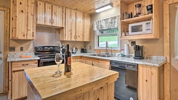 A kitchen with wooden cabinets, a granite countertop, a wine bottle, and a dishwasher.