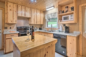 Eine Küche mit Holzschränken, einer Granit Arbeitsplatte, einer Weinflasche und einem Geschirrspüler.