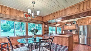 A kitchen with a brick floor, wooden cabinets, a stainless steel refrigerator, and a dining area with a glass table and chairs. - 2-home Country Estate Near Clayton! 2 Hot Tubs (Clayton)
